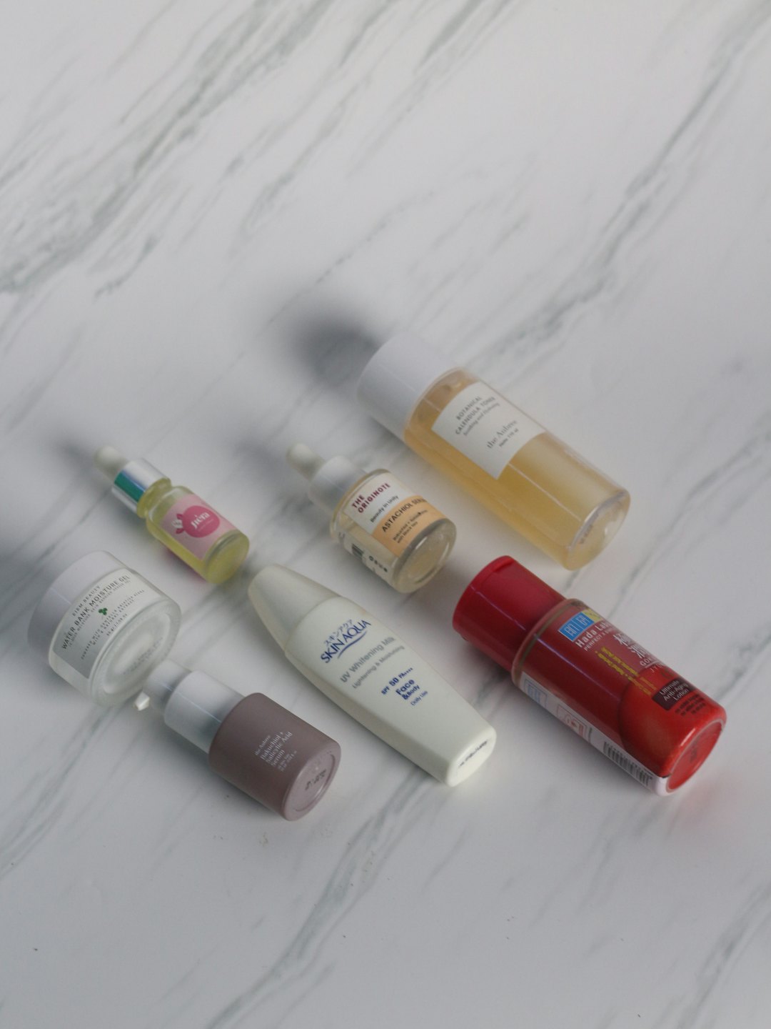 Various skincare bottles and jars arranged on a marble surface.