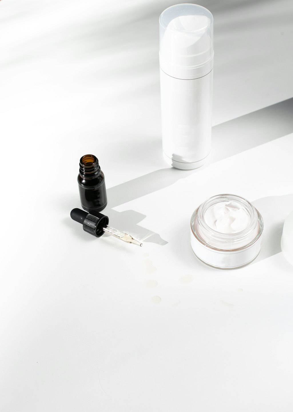 Skincare bottles and jar arranged on a white surface.