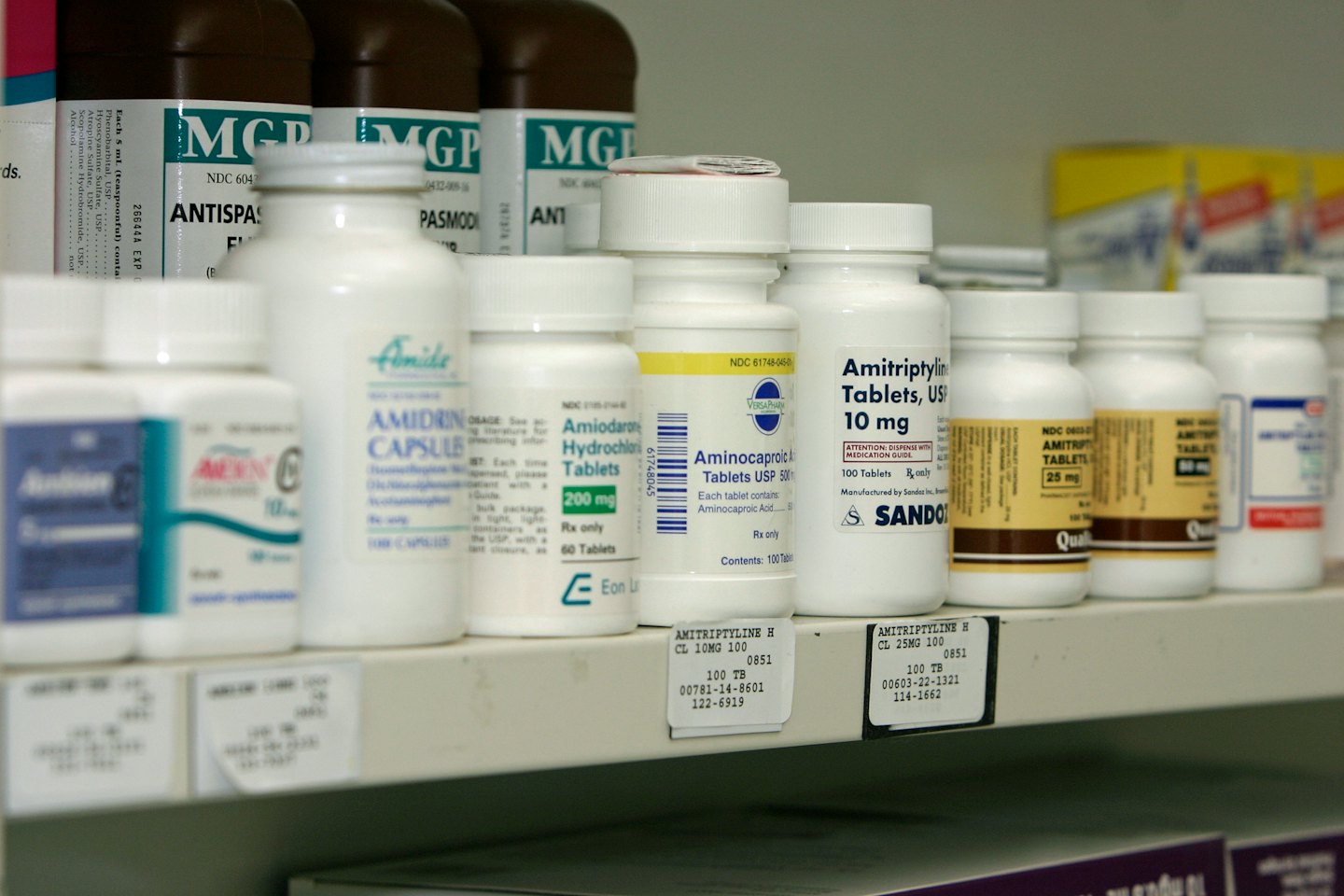 Medication bottles arranged neatly on a white pharmacy shelf.