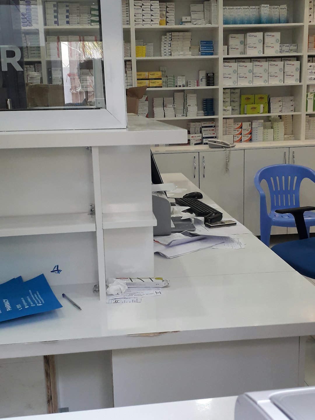 Pharmacy counter stocked with medicines and computer workstation.